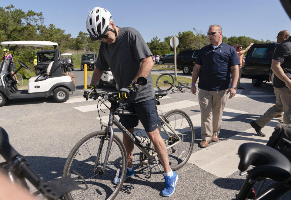 President Joe Biden gets back on his bike after he fell when he tried to get off his bike to greet a crowd at Gordons Pond in Rehoboth Beach, Del., Saturday, June 18, 2022. (AP Photo/Manuel Balce Ceneta)