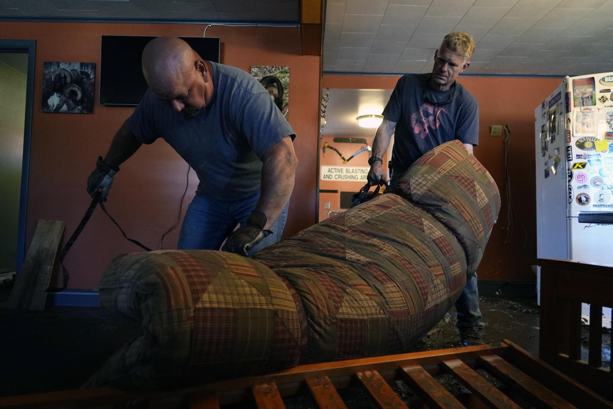 Marvin Rodenbeck and Mac Dean move a soaked futon from a motel basement Thursday, June 16, 2022, in Red Lodge, Mont. The Yodeler Motel was one of about 250 buildings that flooded in Carbon County when torrential rains swelled waterways across the Yellowstone region. (AP Photo/Brittany Peterson)