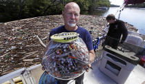 <p>Activist Rocky Morrison, of the “Clean River Project”, holds up a fish bowl filled with hypodermic needles, that were recovered during 2016, on the Merrimack River next to their facility in Methuen, Mass. Morrison leads a cleanup effort along the Merrimack River, which winds through the old milling city of Lowell, and has recovered hundreds of needles in abandoned homeless camps that dot the banks, as well as in piles of debris that collect in floating booms he recently started setting. (Photo: Charles Krupa/AP) </p>