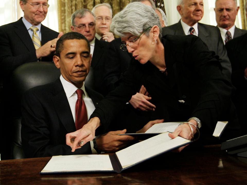 White House staff secretary Lisa Brown helps President Barack Obama as he signs a series of executive orders on the third day of his presidency in 2009.