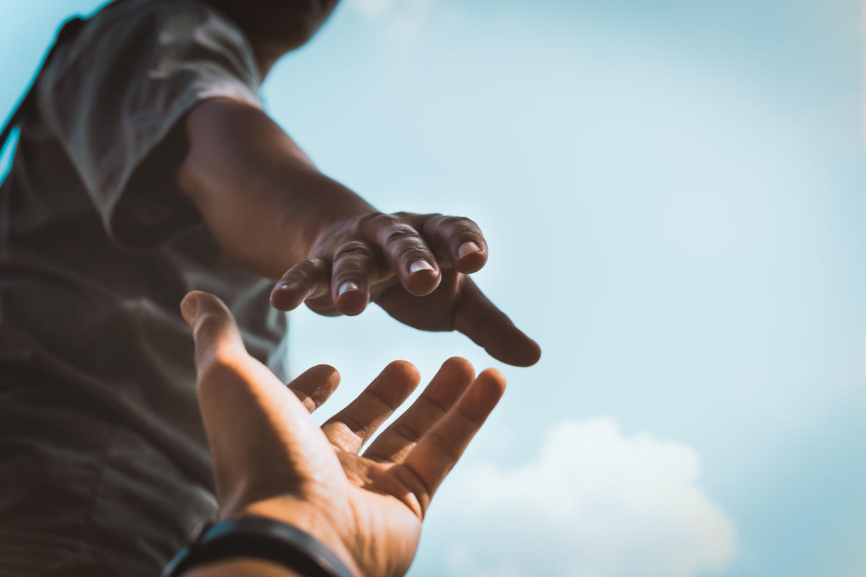 Cropped hands reaching out to help each other against sky,Thailand