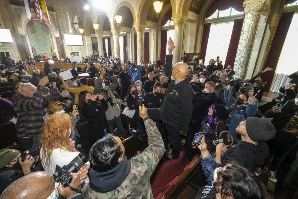 Un hombre de pie entre los asientos del público grita lemas durante una reunión del Concejo Municipal de Los Ángeles, en Los Ángeles, el martes 13 de diciembre de 2022. (AP Foto/Ringo H.W. Chiu)