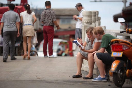 Tourists consult a map at as they sit on a street in Beijing on July 12. Bad news from South Korea, Singapore and China this week failed to rattle investors' confidence in the region, despite fears that Europe's economic contagion is spreading rapidly to the East