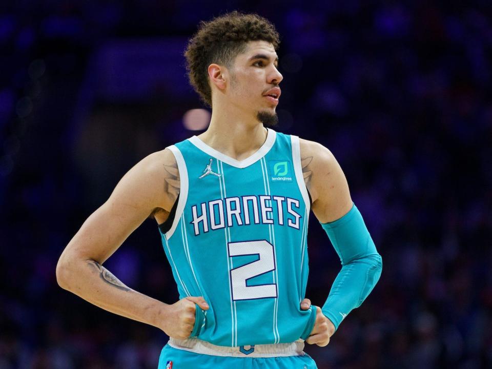 LaMelo Ball looks to his left while standing with his hands on his hips during a Hornets game in 2022.