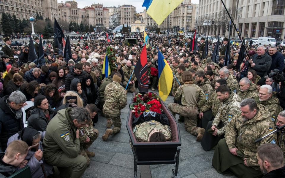 People bow their heads and kneel around the coffin - REUTERS