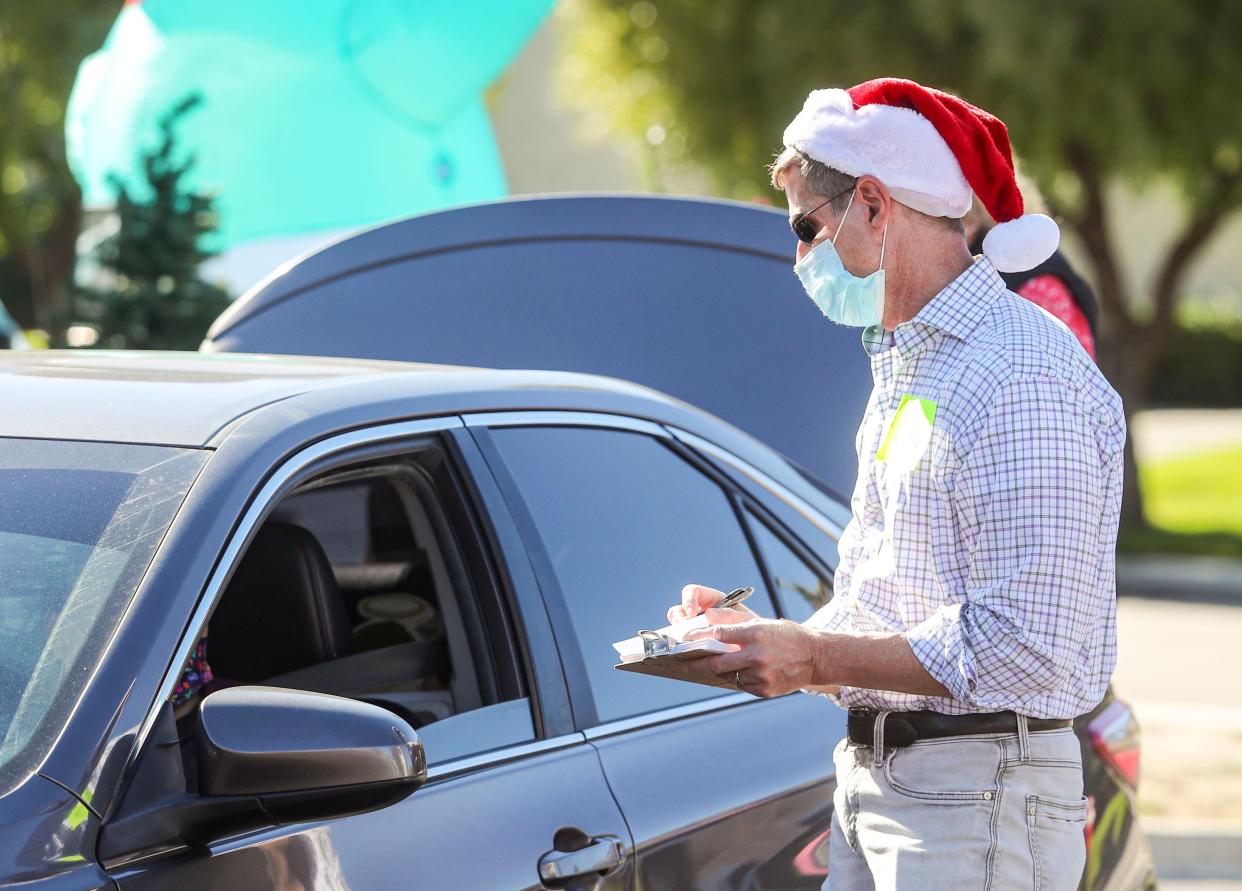 Volunteer Chris Shirley takes orders from cars participating in the mobile Christmas event at United Methodist Church, Saturday, Dec. 18, 2021, in Palm Springs, Calif. 