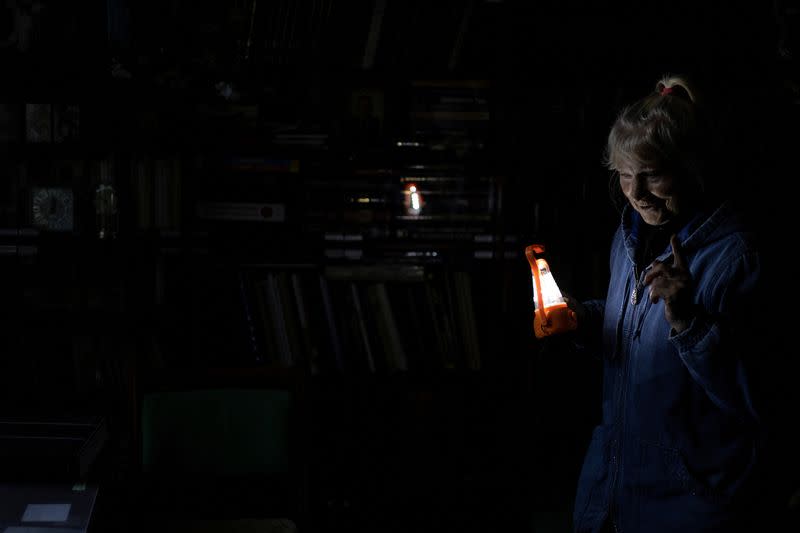 Olga Kobzar stands in her living room as she holds a battery light in her apartment in Saltivka neighbourhood of Kharkiv