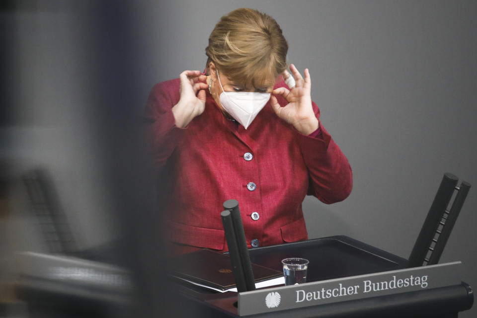German Chancellor Angela Merkel adjust her face mask after her speech during a parliament session about a new law to battle the coronavirus pandemic at the parliament Bundestag in Berlin, Germany, Friday, April 16, 2021. (AP Photo/Markus Schreiber)
