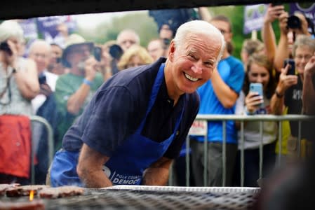 Biden leans down and smiles for media while frying steaks at Polk County Democrats' Steak Fry in Des Moines