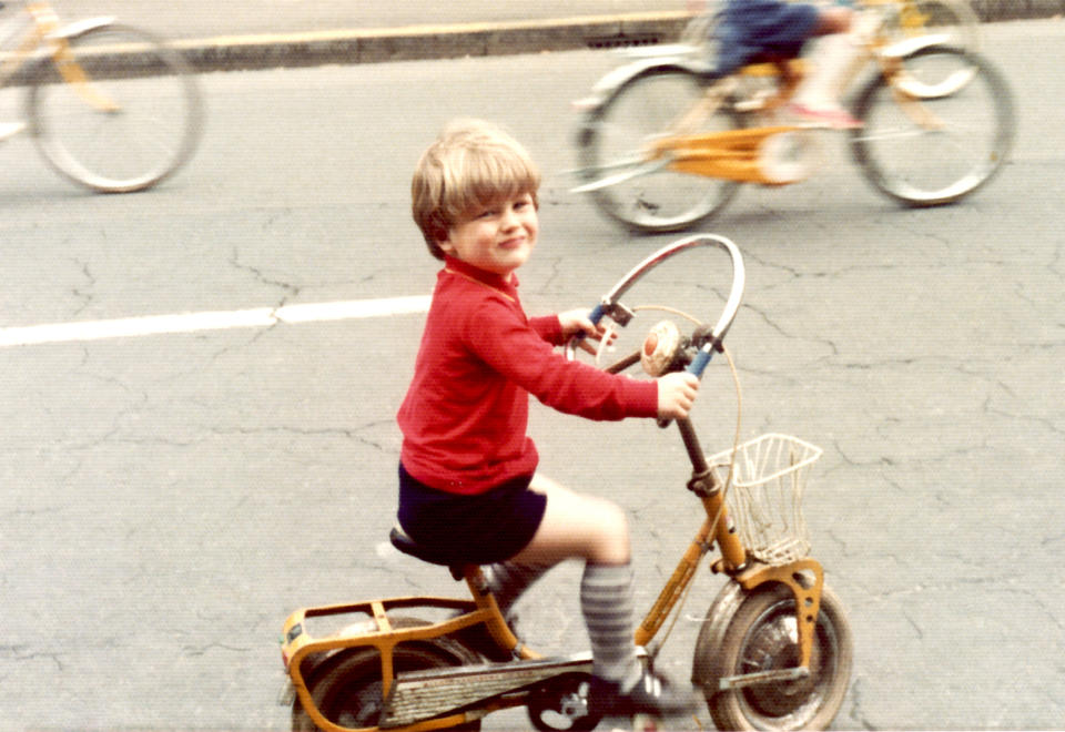 A little boy is riding his bike with the other kids