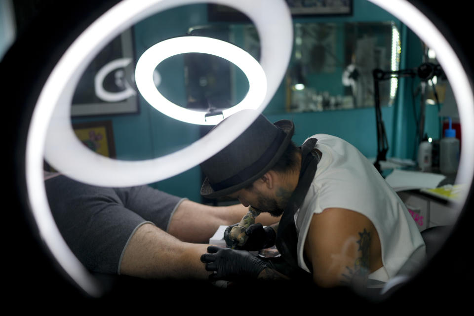 Artist Dario Vivas tattoos Santiago Sposto's leg featuring soccer player Lionel Messi with the World Cup trophy, in Buenos Aires, Argentina, Wednesday, Dec. 28, 2022. (AP Photo/Natacha Pisarenko)