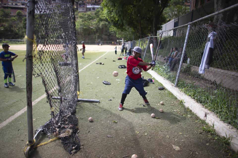 In this Aug. 12, 2019 photo, a young baseball player works at a practice hitting station at Las Brisas de Petare Sports Center, in Caracas, Venezuela. More than 100 boys train daily on the baseball field using old bats, balls and gloves, in hopes of achieving a professional baseball career in the United States. (AP Photo/Ariana Cubillos)