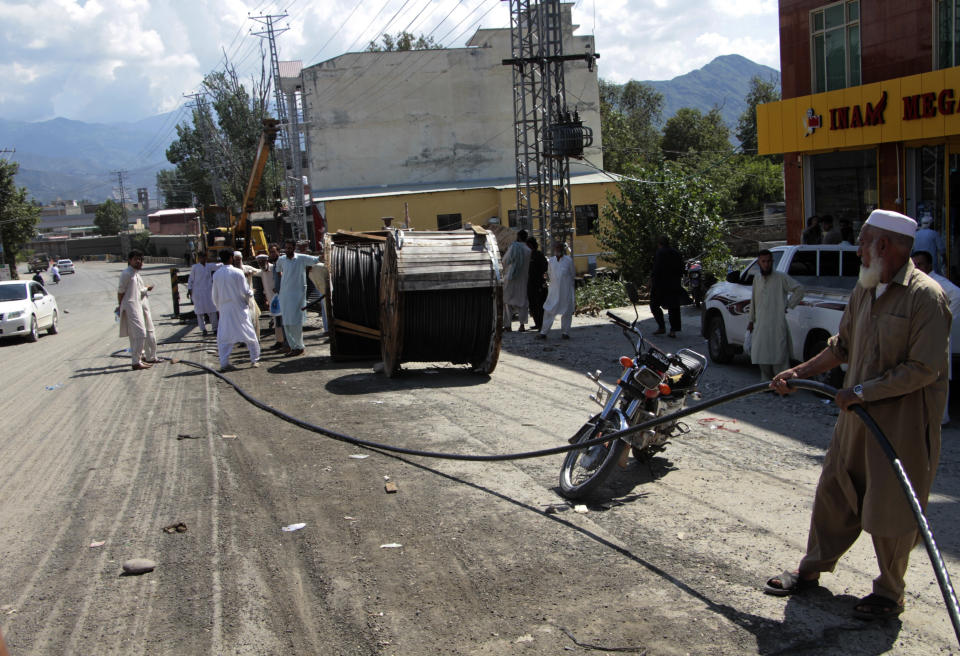 Government workers repair electricity cables to restore services damaged by flooding, in Kanju, Swat Valley, Pakistan, Monday, Aug. 29, 2022. International aid was reaching Pakistan on Monday, as the military and volunteers desperately tried to evacuate many thousands stranded by widespread flooding driven by "monster monsoons" that have claimed more than 1,000 lives this summer. (AP Photo/Naveed Ali)