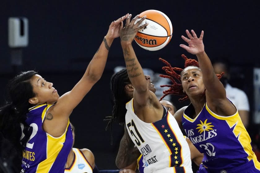 Indiana Fever forward Jessica Breland, center, reaches for a rebound along with Los Angeles Sparks guard Arella Guirantes.