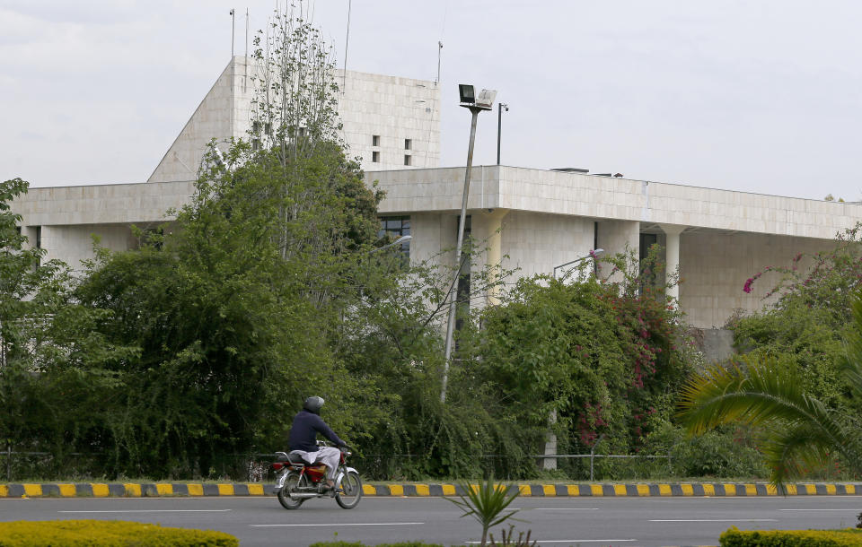 A motorcyclist rides past the French Embassy, in Islamabad, Pakistan, Thursday, April 15, 2021. The French embassy in Pakistan on Thursday advised all of its nationals and companies to temporarily leave the country after anti-France violence erupted in the Islamic nation over the arrest of a radical leader. Saad Rizvi was arrested Monday for threatening the government with mass protests if it did not expel French envoy Marc Baréty over the publication depictions of Islam’s Prophet Muhammad. (AP Photo/Anjum Naveed)