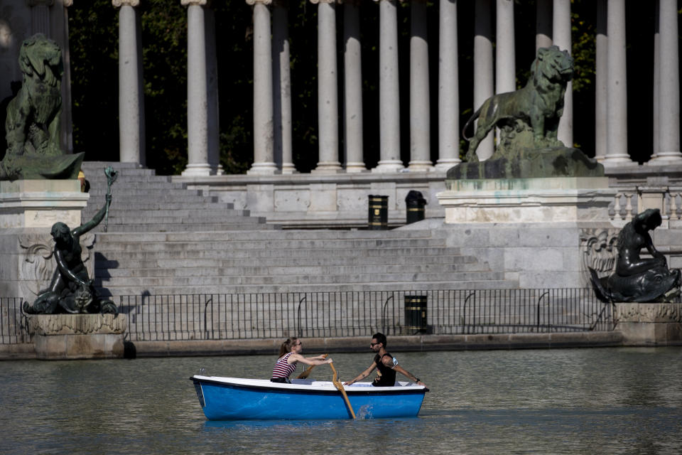 A couple sail a boat during a hot day of summer at the Retiro park in Madrid, Spain, Wednesday, July 29, 2020. The first heat wave of the summer, which will arrive this Thursday and will last at least until next Saturday will leave temperatures over 34 Celsius (104 Fahrenheit). (AP Photo/Manu Fernandez)