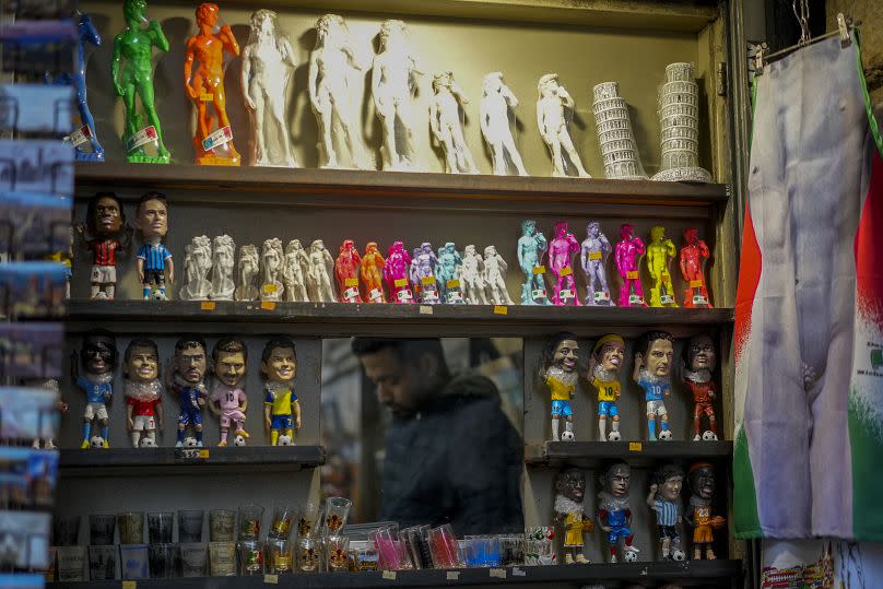 A vendor sells souvenirs of Michelangelo's 16th century statue of David at a kiosk in downtown Florence