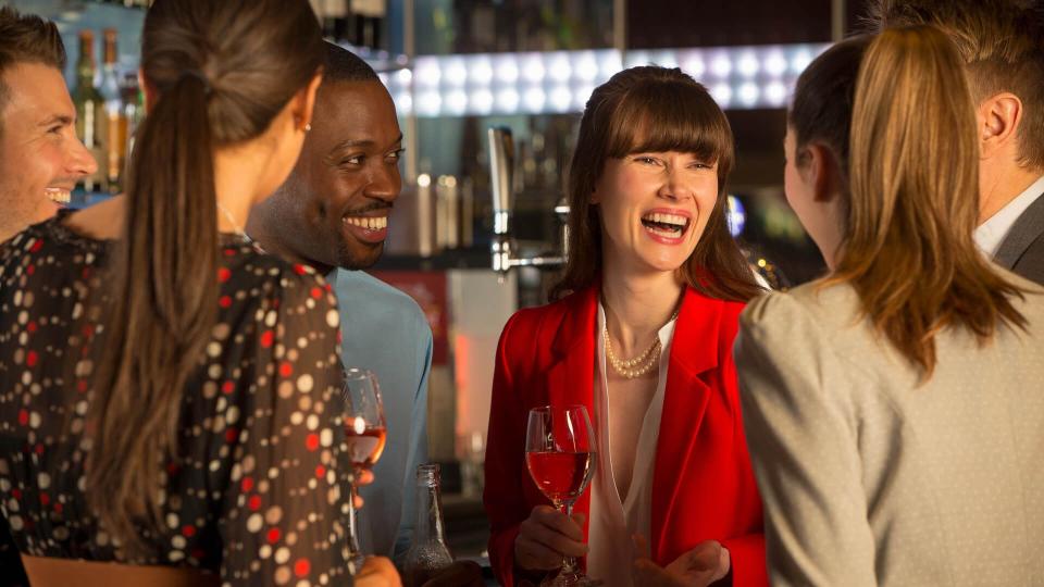 Six young adults can be seen laughing and enjoying a drink in a bar.