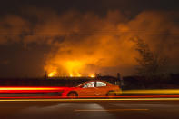 <p>A slow camera shutter speed catches the lights of cars passing spectators sitting in a car off the side of Hwy 137 to watch the volcanic activity from the Malama Ki and Lelani Estates neighborhoods, Thursday, May 17, 2018, near Pahoa, HI. (Photo: Marco Garcia/AP) </p>