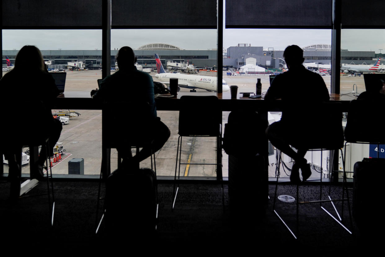 Passengers are seen in silhouette at a Delta Sky Club as an airplane parks at a gate in front of them at Hartsfield-Jackson Atlanta International Airport ahead of the Fourth of July holiday in Atlanta, Georgia, U.S., July 1, 2022.  REUTERS/Elijah Nouvelage