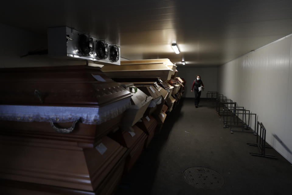 A worker walks past caskets placed inside an overflow cold storage container placed outside a crematorium in Ostrava, Czech Republic, Thursday, Jan. 7, 2021. The biggest crematorium in the Czech Republic has been overwhelmed by mounting numbers of pandemic victims. With new confirmed COVID-19 infections around record highs, the situation looks set to worsen. Authorities in the northeastern city of Ostrava have been speeding up plans to build a fourth furnace but, in the meantime, have sought help from the government’s central crisis committee for pandemic coordination. (AP Photo/Petr David Josek)
