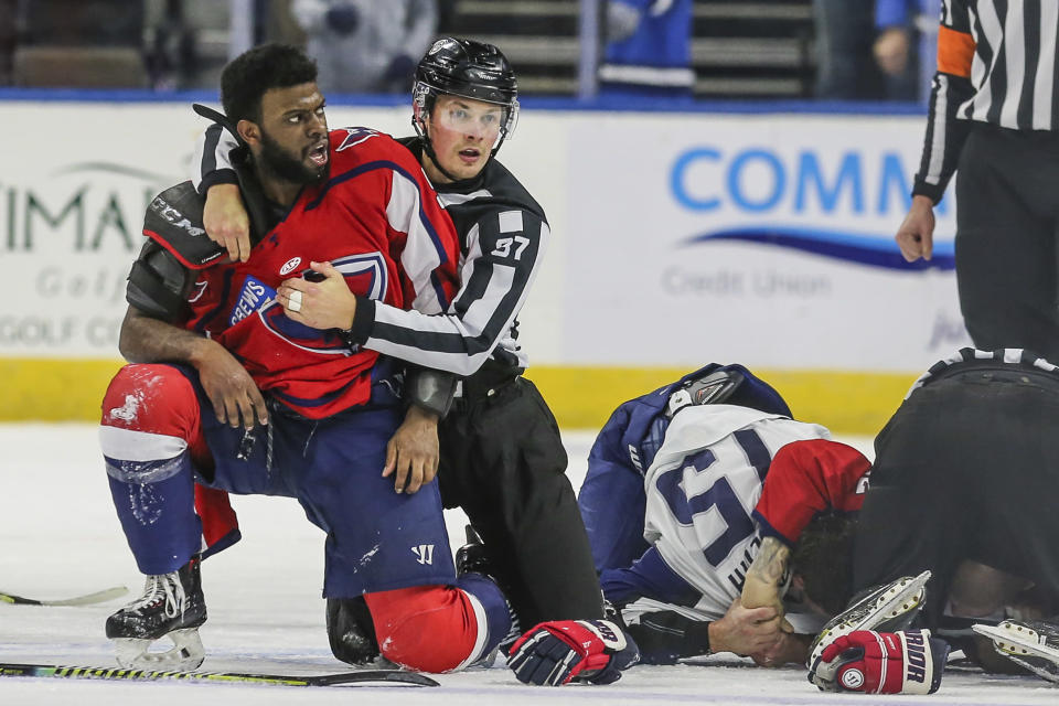 After an on-ice fight, South Carolina Stingrays defenseman Jordan Subban (5), left, is held by linesman Shane Gustafson while Jacksonville Icemen defenseman Jacob Panetta (15) is face-down on the ice engaged with another player during overtime of an ECHL hockey game in Jacksonville, Fla., Saturday, Jan. 22, 2022. The ECHL has suspended Panetta after the brother of longtime NHL defenseman P.K. Subban accused the Jacksonville defenseman of making “monkey gestures” in his direction. (AP Photo/Gary McCullough)