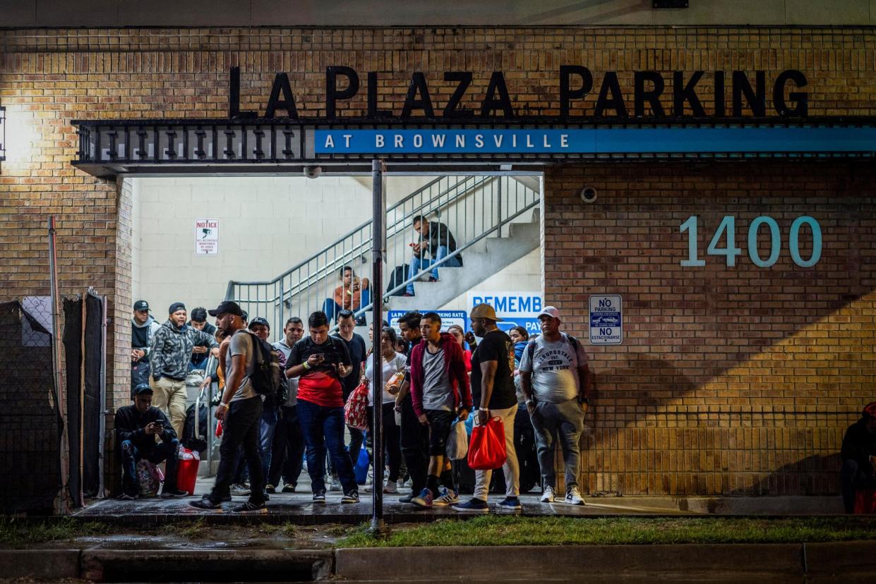 <span>People stand at a processing center in Brownsville, Texas, as they wait for a bus to Chicago on 24 October 2023.</span><span>Photograph: Carlos Barría/Reuters</span>