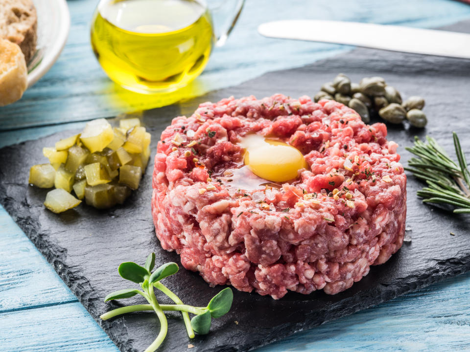 Steak tartare served with raw quail egg yolk, capers and bread. Meat dish.
