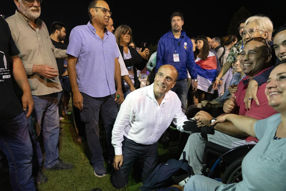 Uruguay's presidential candidate for the ruling Broad Front political party, Daniel Martinez, poses for a photo with a disabled supporter during a cultural event in Montevideo, Uruguay, Tuesday, Nov. 19, 2019. Uruguay will hold run-off presidential elections on Nov. 24 between Daniel Martinez and the presidencial candidate for the National Party, Luis Lacalle Pou . (AP Photo/Matilde Campodonico)