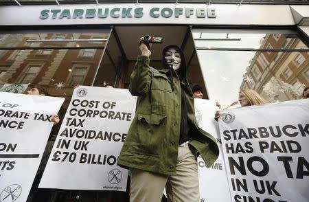 A masked demonstrator leaves a Starbucks coffee shop in central London December 8, 2012. REUTERS/Luke MacGregor
