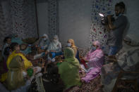 Relatives and neighbors of Kashmiri groom Haseeb Mushtaq, sing during henna ceremony of his wedding in Srinagar, Indian controlled Kashmir, Sunday, Sept. 13, 2020. The coronavirus pandemic has changed the way people celebrate weddings in Kashmir. The traditional week-long feasting , elaborate rituals and huge gatherings have given way to muted ceremonies with a limited number of close relatives attending. With restrictions in place and many weddings cancelled, the traditional wedding chefs have little or no work. The virus has drastically impacted the life and businesses in the region. (AP Photo/ Dar Yasin)