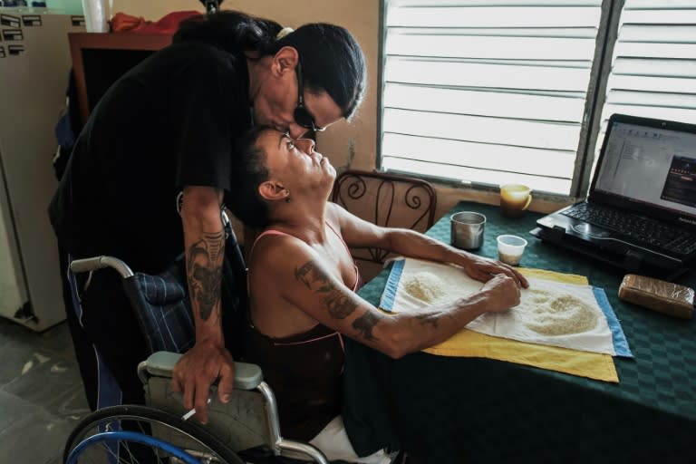 Gerson Govea kisses his wife Yohandra Cardoso while she cleans rice at their home, a former sanatorium for HIV patients in Pinar del Rio province, Cuba, where they met in 2000