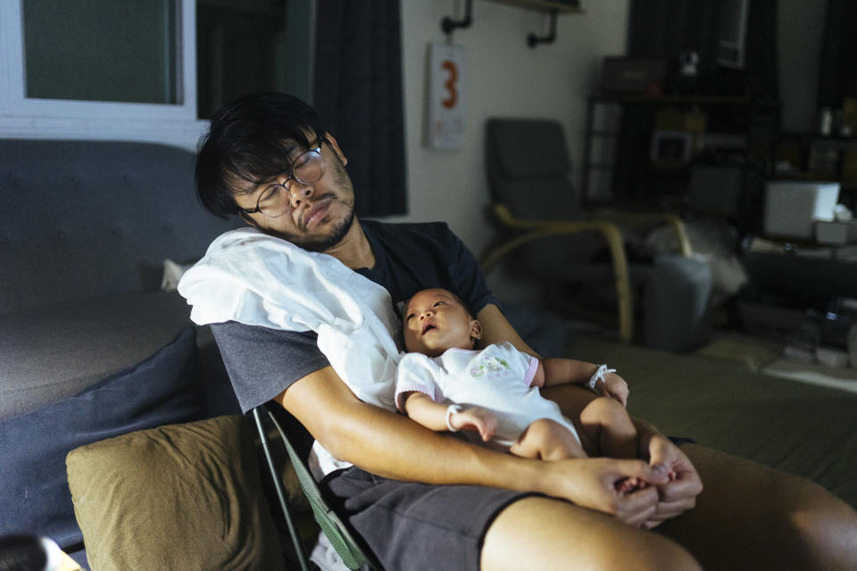 A man sleeping with a baby in his hand