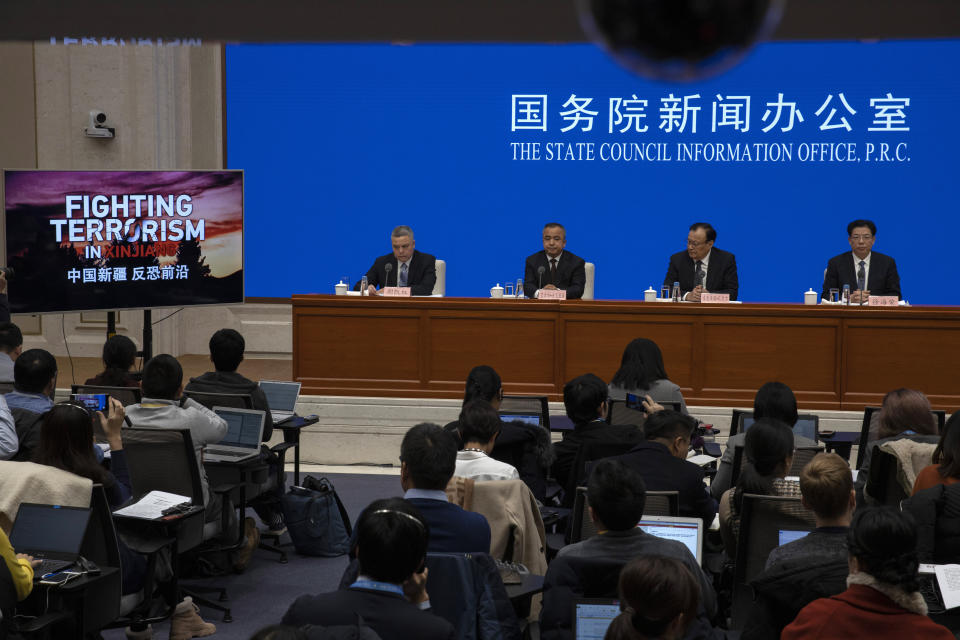 Shohrat Zakir, chairman of China's Xinjiang Uighur Autonomous Region, second from right looks at a screen displaying a documentary titled "Fighting Terrorism in Xinjiang" during a press conference in Beijing on Monday, Dec. 9, 2019. (AP Photo/Ng Han Guan)