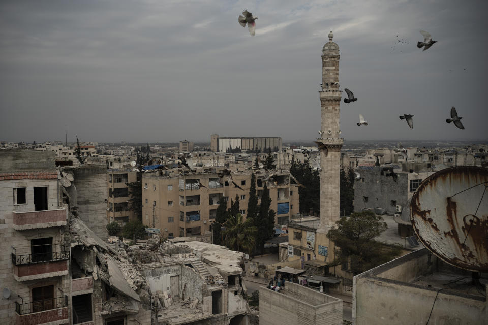In this Thursday, March 12, 2020 photo, a mosque stands next to a a damaged building, in Idlib, Syria. Idlib city is the last urban area still under opposition control in Syria, located in a shrinking rebel enclave in the northwestern province of the same name. Syria’s civil war, which entered its 10th year Monday, March 15, 2020, has shrunk in geographical scope -- focusing on this corner of the country -- but the misery wreaked by the conflict has not diminished. (AP Photo/Felipe Dana)