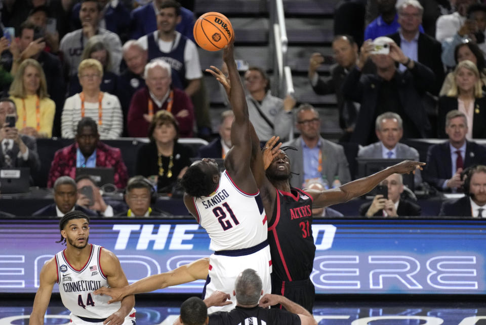 Connecticut forward Adama Sanogo (21) and San Diego State forward Nathan Mensah (31) fight for the opening tip during the first half of the men's national championship college basketball game in the NCAA Tournament on Monday, April 3, 2023, in Houston. (AP Photo/Godofredo A. Vasquez)