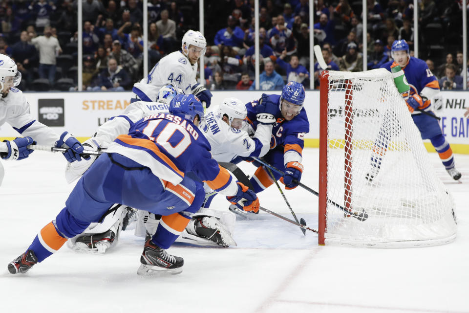 New York Islanders' Anders Lee (27) and Derick Brassard (10) and Tampa Bay Lightning's Luke Schenn (2) reach for a puck shot by Islanders' Mathew Barzal (13) for a goal during the second period of an NHL hockey game Friday, Nov. 1, 2019, in Uniondale, N.Y. (AP Photo/Frank Franklin II)