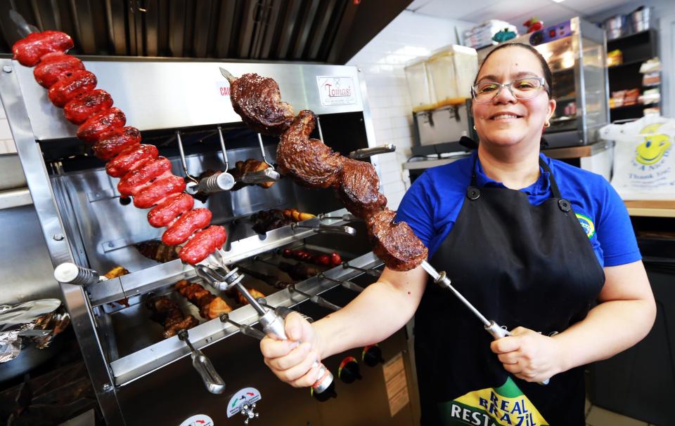 Owner and chef Andreia Mourao shows off linguica and steak coming off the barbecue for the lunch hour at Real Brazil Restaurant and Market on Tremont Street in Taunton on Thursday, April 14, 2022. 