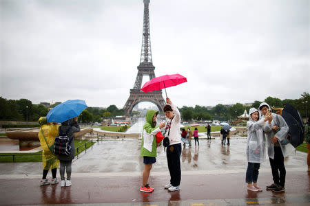 Tourists stroll on the Trocadero square, in front of the Eiffel Tower during a rainy day in Paris, France, May 30, 2016. REUTERS/Charles Platiau