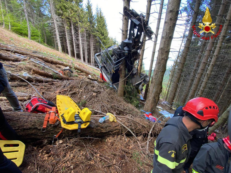 Rescuers work by the wreckage of a cable car after it collapsed near the summit of the Stresa-Mottarone line in the Piedmont region, northern Italy, Sunday, May 23, 2021. A cable car taking visitors to a mountaintop view of some of northern Italy's most picturesque lakes plummeted to the ground Sunday and then tumbled down the slope, killing at least 13 people and sending two children to the hospital, authorities said. (Italian Vigili del Fuoco Firefighters via AP)