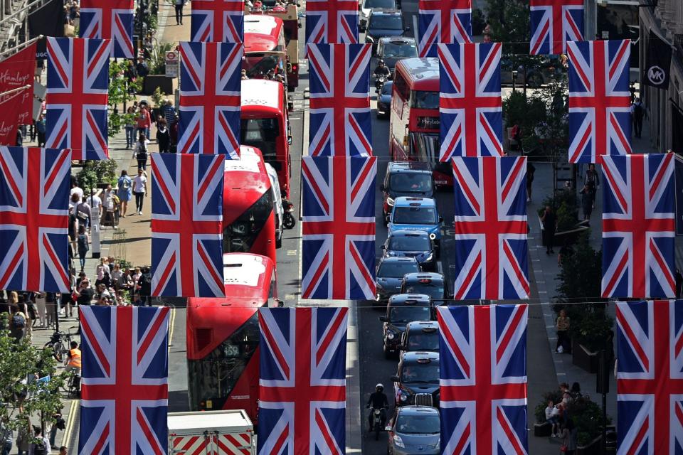 Red London buses and taxis pass beneath British flags celebrating Queen Elizabeth's Platinum Jubilee, in Regent Street in central London on May 27, 2022.