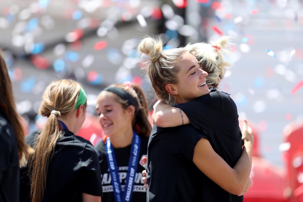 Kristie Mewis and Jane Campbell hug with confetti in the background. 