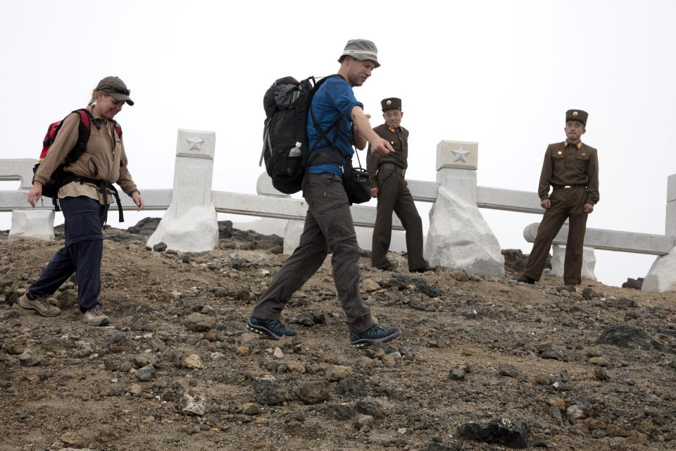 In this Saturday, Aug. 18, 2018, file photo, Sinead of Australia, left, and Tarjei Naess Skrede of Norway walk past North Korean soldiers during a hike arranged by Roger Shepherd of Hike Korea on Mount Paektu in North Korea. Hoping to open up a side of North Korea rarely seen by outsiders, Shepherd, a New Zealander who has extensive experience climbing the mountains of North and South Korea is leading the first group of foreign tourists allowed to trek off road and camp out under the stars on Mount Paektu, a huge volcano that straddles the border that separates China and North Korea. (AP Photo/Ng Han Guan, File)