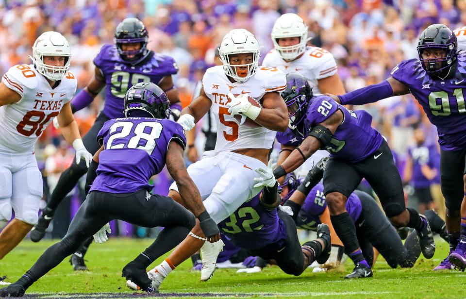 Texas running back Bijan Robinson (5) runs with the ball as TCU  safety La'Kendrick Van Zandt (20) and safety Nook Bradford (28) defend during the first quarter at Amon G. Carter Stadium.