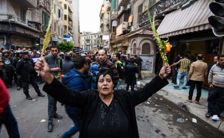 An Egyptian woman raises braided palm leaves, originally intended for Palm Sunday celebrations, during a gathering outside the Coptic Orthodox Patriarchate in Alexandria after a bomb blast struck outside while worshippers attended Palm Sunday mass on April 9, 2017