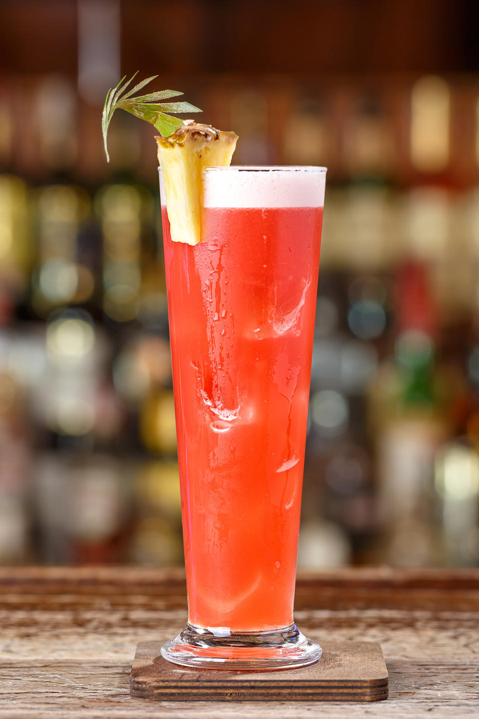 Singapore sling cocktail with gin, cherry and orange liqueur Benedict, grenadine, pineapple and lemon juice with the addition of bitter Angostura. Cocktail on the background of the bar in the nightclub