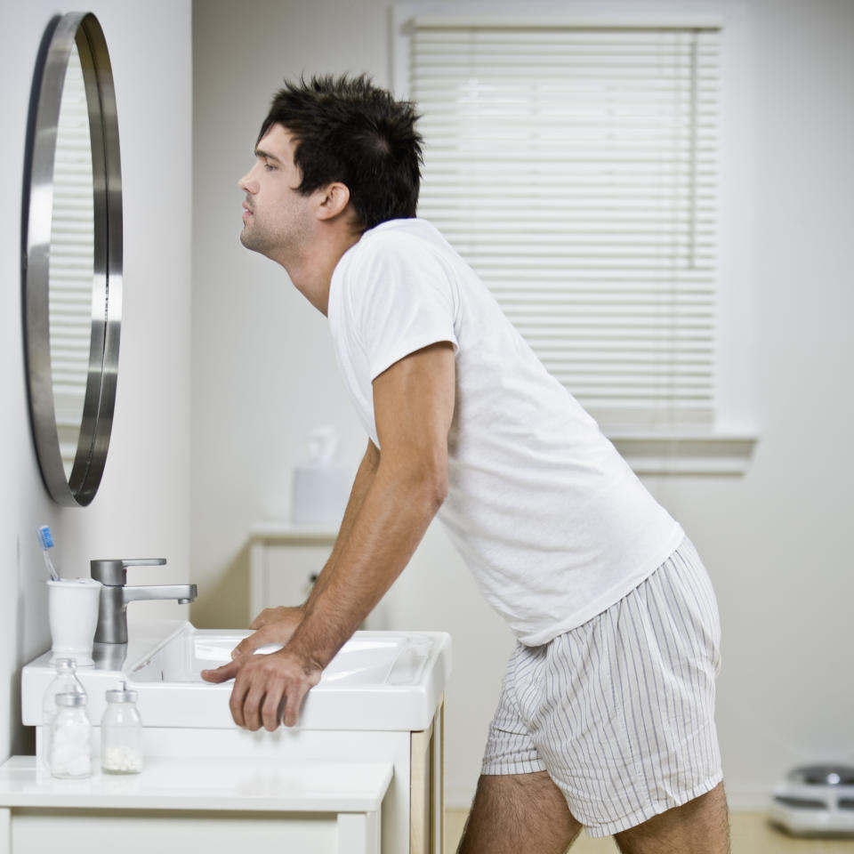 A man looking into a mirror in his pajamas