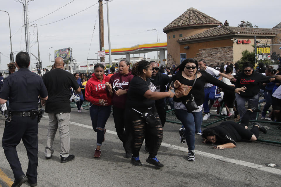 People flee the scene after hearing a loud noise while waiting for a hearse carrying the casket of slain rapper Nipsey Hussle Thursday, April 11, 2019, in Los Angeles. The 25-mile procession traveled through the streets of South Los Angeles, including a trip past Hussle's clothing store, The Marathon, where he was gunned down March 31. (AP Photo/Jae C. Hong)