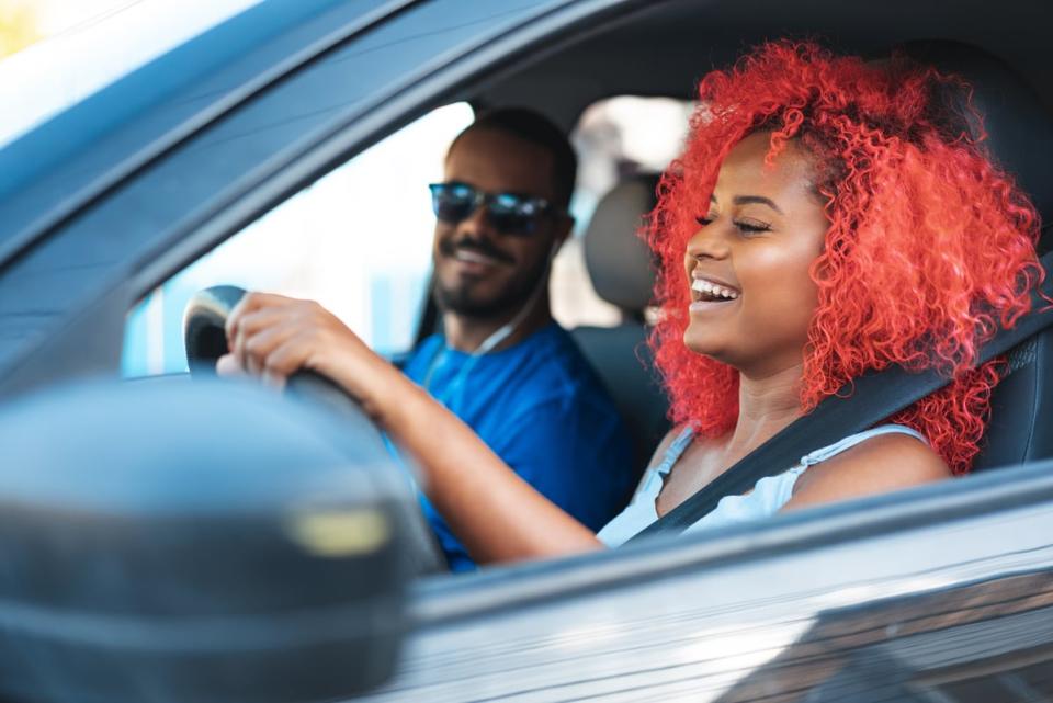 Two people smiling in the front seats of a car.