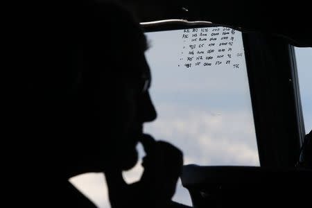 A crew member aboard a Royal New Zealand Air Force P-3K2 Orion aircraft is pictured alongside handwritten notes of other search craft in the area, during a search for the missing Malaysian Airlines flight MH370 over the southern Indian Ocean in this March 29, 2014 file photo. REUTERS/Jason Reed/Files